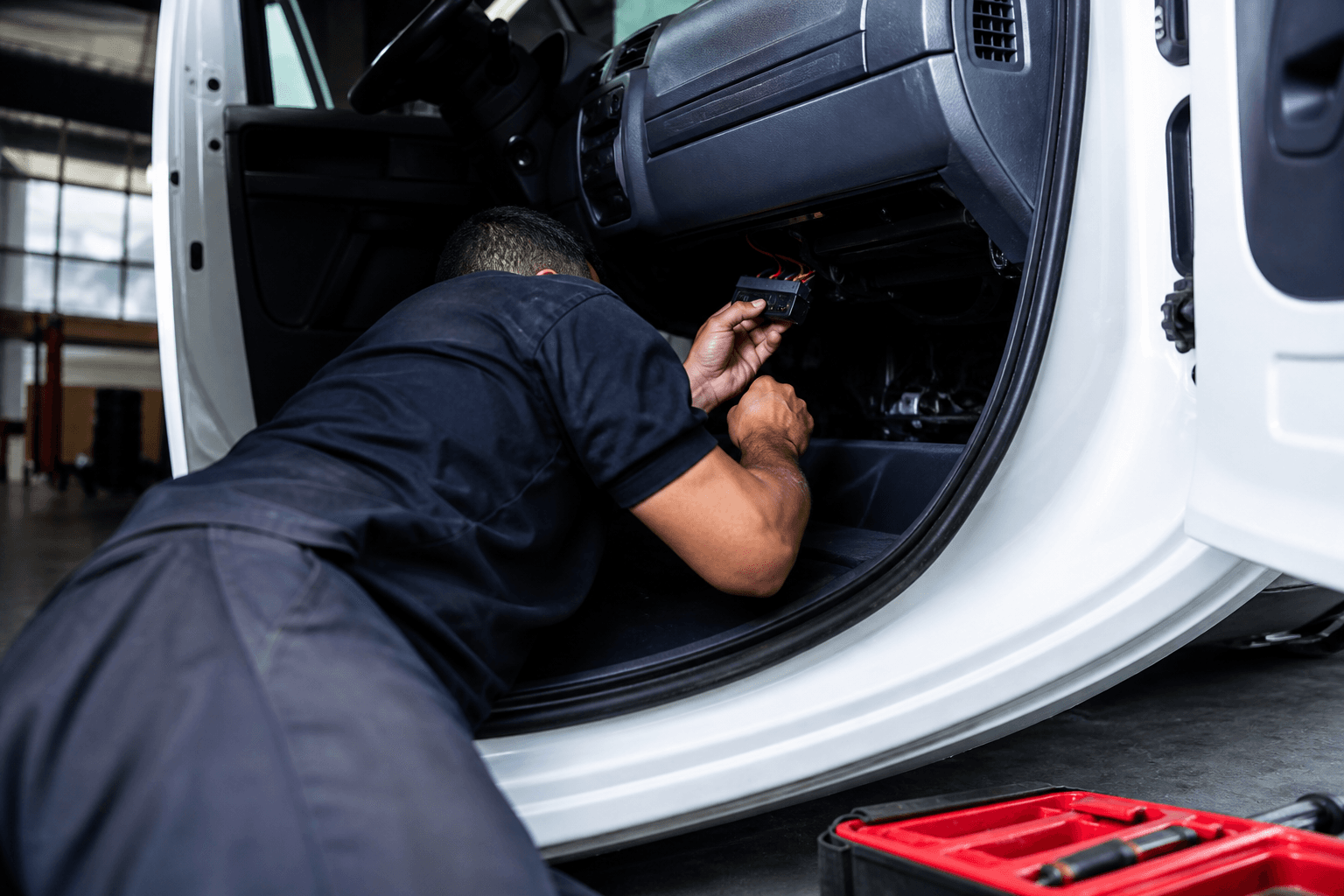 Técnico instalando rastreador veicular no painel de um utilitário de frota